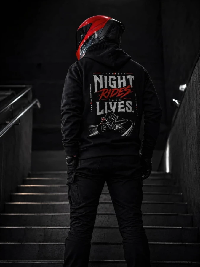 Bluza Night Rides Save Lives FEARLESS prezentowana na schodach z widocznym nadrukiem na plecach w nocnym klimacie.